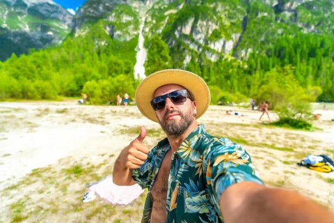 Happy tourist showing thumbs up while taking a selfie at lago di landro, also known as durrensee