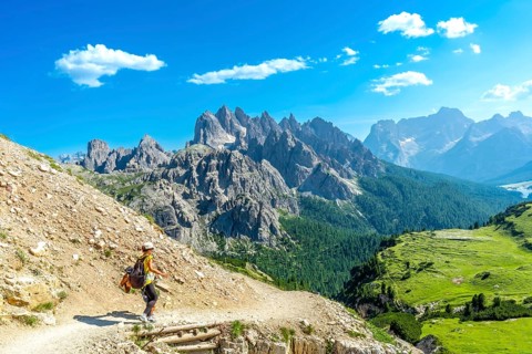 Female tourist hiking on a mountain trail with breathtaking views of the tre cime di lavaredo peaks