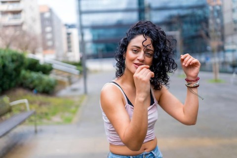 Stylish young woman with curly hair enjoying dancing outdoors, showcasing urban lifestyle and