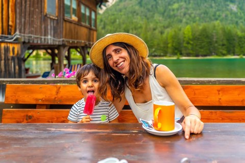 Tourists enjoying a summer day with ice cream and coffee by a mountain lake in the italian alps