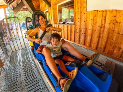 A woman and a child are riding a roller coaster. The woman is holding the child's hand