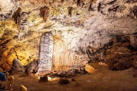 Tourists riding a train admiring the illuminated stalagmites and stalactites inside the famous
