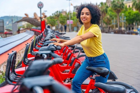 Portrait of a latin young woman smiling at camera while using rental public bike service