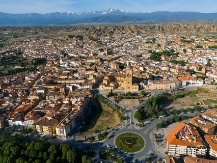 Aerial view of a city with historical centre, roundabout and green parks, surrounded by landscape