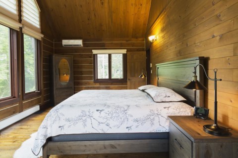 King size bed on wood-frame with wooden headboard, nightstand with antique industrial style lamp,