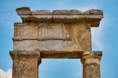 Close-up of an ancient stone gate with fine carvings and blue sky in the background, Well house,