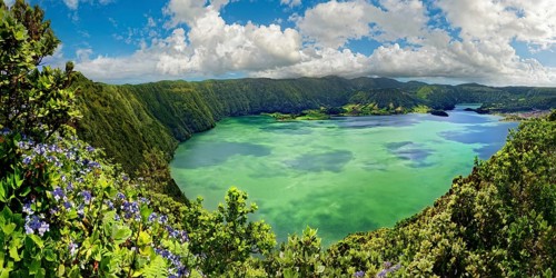 Breathtaking panoramic view of the crater lake Lagoa Azul surrounded by steep rock faces under a