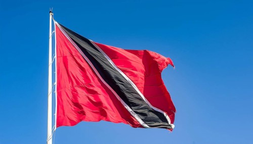 The flag of Tobago, Caribbean, flutters in the wind, isolated against a blue sky