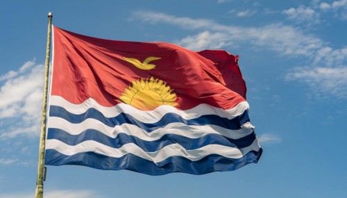 The flag of Kiribati, Polynesia, flutters in the wind, isolated against a blue sky