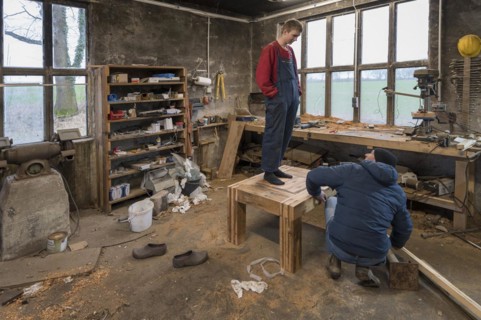 Young man tests the durability of his Tiasch in the workshop, his father looks on,