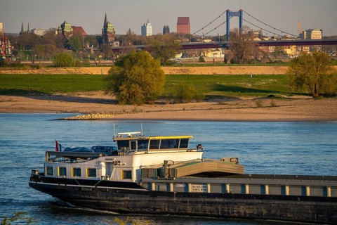 Cargo ship on the Rhine near Duisburg-Beeckerwerth, skyline of the city centre, with town hall,
