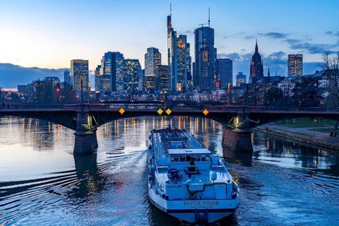 Skyline of the city centre of Frankfurt am Main, river Main, dusk, Ignatz-Bubis-Bridge, cargo ship,