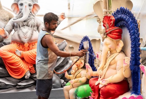 An artisan decorates an idol of the elephant-headed Hindu deity Ganesha at a workshop ahead of the