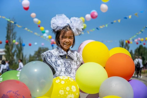 Happy schoolgirl with colourful balloons on the first day of school, Issyk-Kul region, Kyrgyzstan,