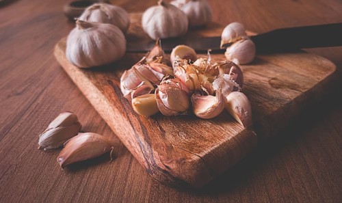 Fresh garlic on a chopping board, wooden table, knife, rustic, mobile photo, no people