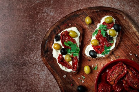 Sandwich with cream cheese, dried tomatoes, olives, breakfast, top view