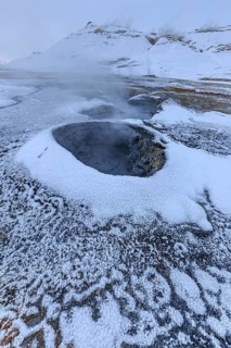 Hot springs and geothermal area in front of a mountain landscape in winter, cloudy mood, Hverir,