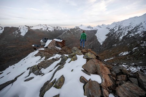 Mountaineer looking at mountain panorama and glacier, mountain hut Ramolhaus in autumn with snow,