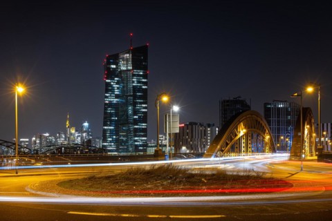 The lights of the European Central Bank (ECB) and the Frankfurt banking skyline glow in the