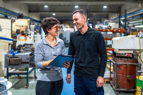 Female boss and worker talking happily and animatedly in a cnc factory