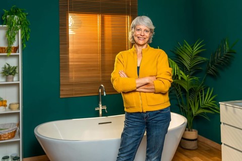 Casual caucasian mature woman standing with arms crossed on a modern bathroom