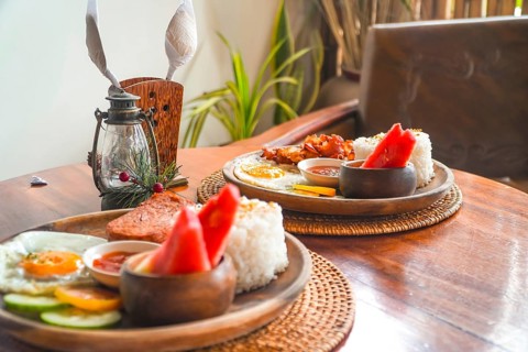 Two plates of filipino breakfast featuring tocino, fried rice, fried egg, watermelon, cucumber, and
