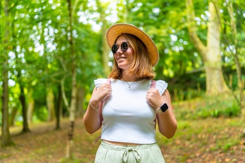 Beauty female caucasian tourist wearing sun hat and sunglasses walking along a green forest in