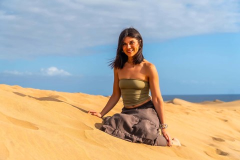 Young woman relaxing and enjoying a sunny day sitting on the sand of the maspalomas dunes in gran