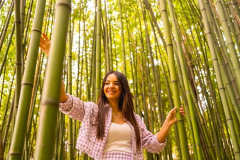 Young caucasian girl with a pink skirt in a bamboo forest. Enjoying summer holidays in a tropical