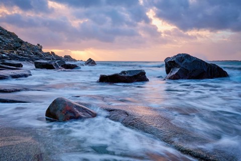 Rocks on beach of fjord of Norwegian sea in winteron sunset. Utakliev beach, Lofoten islands,