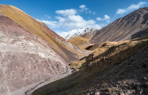 Valley with mountain stream between high mountains in autumn, mountain landscape with glaciated