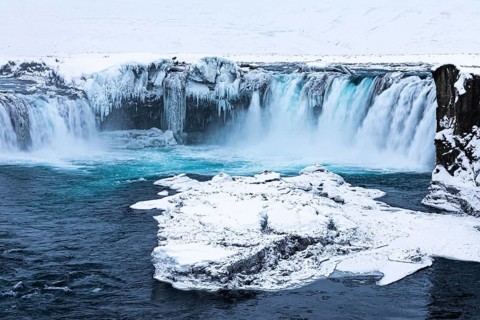 Ice layer in the river Skialfandaljot, behind it the waterfall Godafoss, Northern Iceland Eyestra,