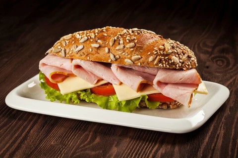 Ham sandwich with lettuce, cheese, tomato on plate on wooden table