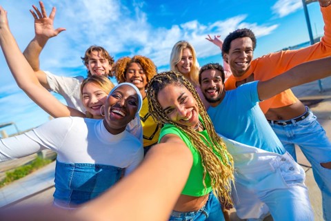 Multi-ethnic friends smiling at camera while taking a funny selfie in the city