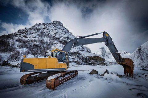 Old excavator with excavator bucket in winter. Road construction in snow. Lofoten islands, Norway,