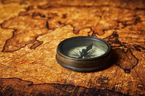 Old vintage retro compass on ancient world map close up
