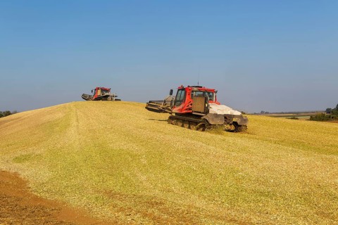 Piston Bully tracked bulldozer vehicles building silage clamp of sweetcorn maize in field stored