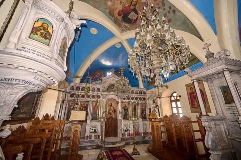 A magnificently decorated church interior with chandeliers, an ornate altar and colourful icons,