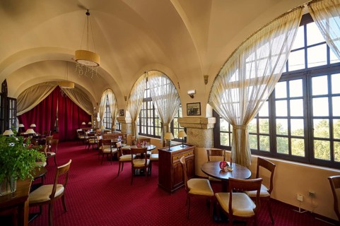 Elegant interior of a restaurant with red carpets, curtains, arched windows and table groups,