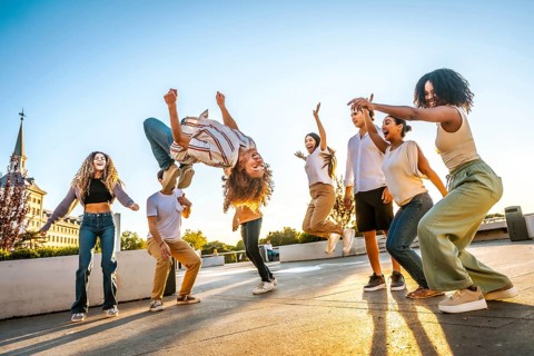 Man jumping dancing free style surrounded by multi-ethnic friends in the city during sunset