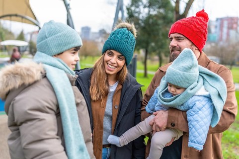 Smiling family wearing winter clothes spending time together at the playground on a cold day