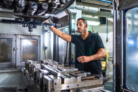 Male caucasian technician working with milling machine in a cnc metallurgic factory