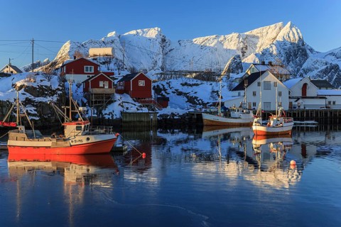 Fishing boats in fjord in front of snowy mountains, morning light, winter, Reine, Moskenesoya,