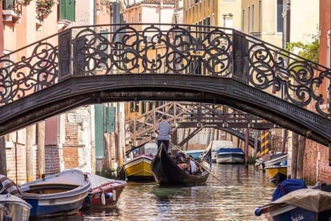 Venetian gondola with gondolier travelling on the canals of Venice, Venice, Italy, Europe
