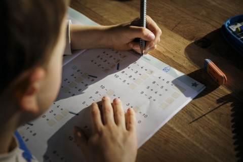 A six-year-old boy does first-grade maths homework at home in a workbook. Berlin, 13.03.2024