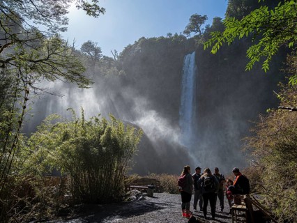 Tourists in front of waterfall Salto El Leon, valley of waterfalls east of Pucon, La Auracania,