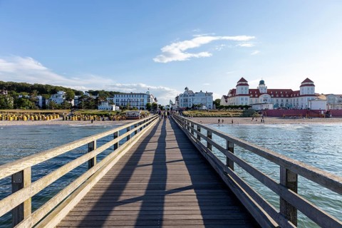 View along a wooden bridge to buildings and the blue sky with few clouds, Rügen, Binz