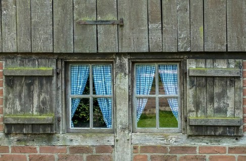 Old wooden window with blue curtains and weathered shutters, Münsterland, North Rhine-Westphalia,