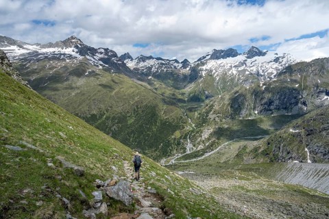 Mountaineer on a hiking trail in front of a picturesque mountain landscape, rocky mountain peaks