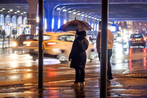 Illuminated subway at the main railway station, pedestrians at a pedestrian crossing, rainy